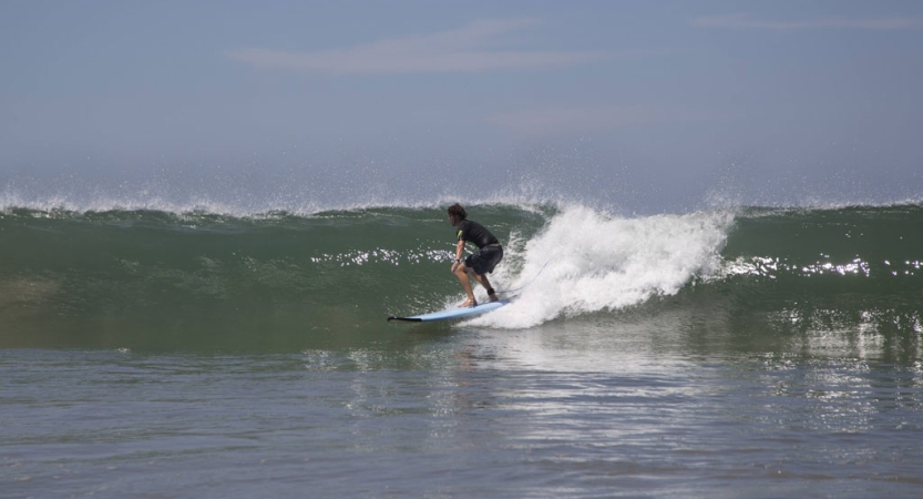 a person surfs on a small wave under blue skies